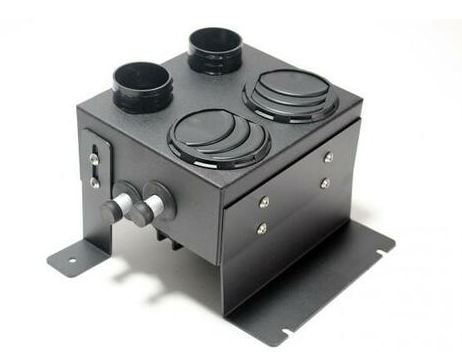 The 2021+ Can Am Commander Inferno Cab Heater W/Defrost is a black metal unit with two round adjustable vents on top, dual pipe connectors in front, two rear circular duct openings, and side mounting brackets. Pictured against a white background.